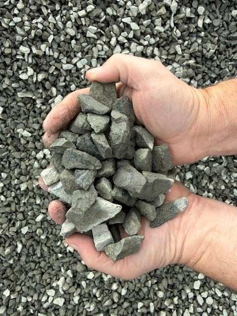 Two hands holding 1 1/4" clean crushed rock