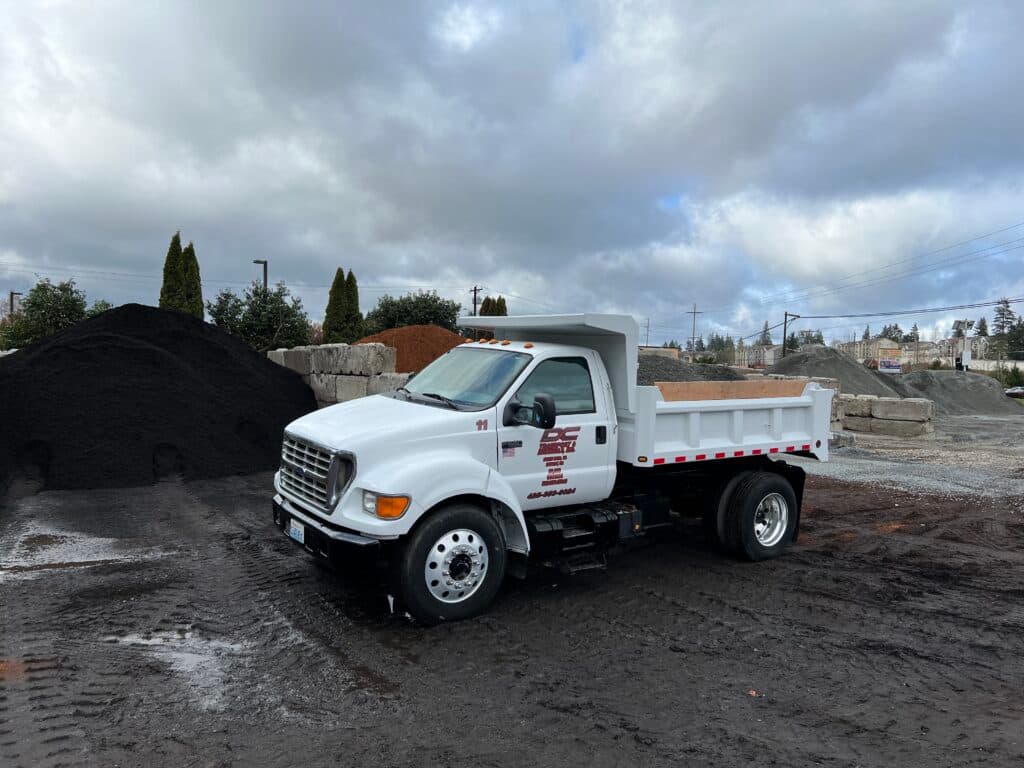 A DC Transport & Materials dump truck beside the piles in the yard